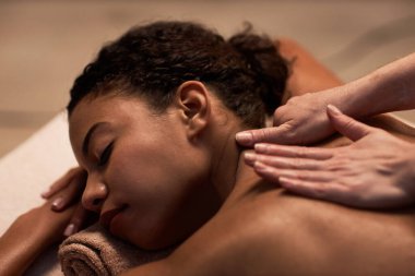 Genç bir kadın boyun ve sırt masajı yaptırıyor.