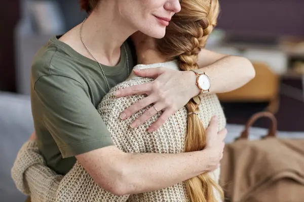 Candid closeup of military mom embracing daughter at home, copy space