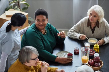 Huzurevinde kahvaltıda yaşlı bir grup genç hemşireye yüksek açılı bir bakış açısı.