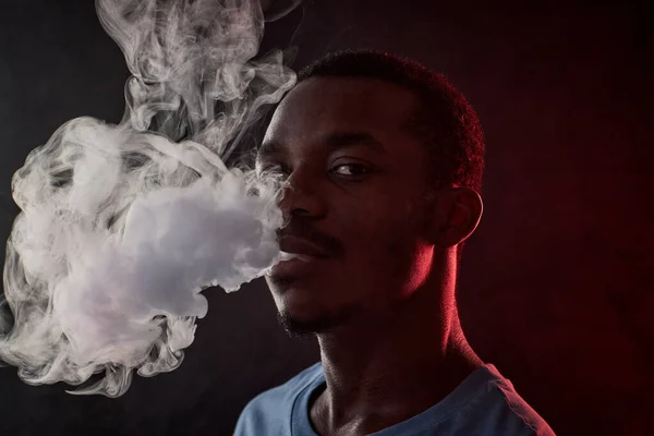 Chico Afroamericano Mirando Cámara Mientras Fuma Oscuridad Soplando Una Gran —  Fotos de Stock