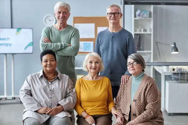 Group portrait of multiethnic seniors posing in medical clinic setting all looking at camera