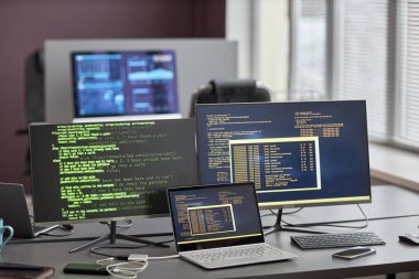 İş yerindeki bilişim bürosunda kod satırları olan birden fazla bilgisayar ekranının arkaplan görüntüsü