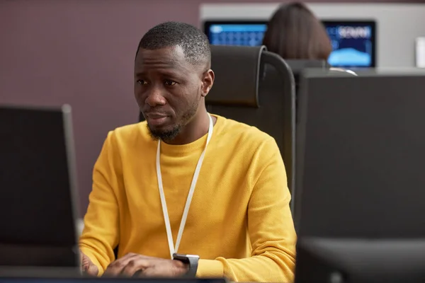 Portrait of black man using computer and typing while working in office at software development company, copy space