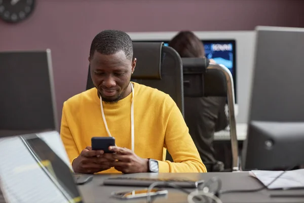 Portrait of black software developer using smartphone at office desk, copy space