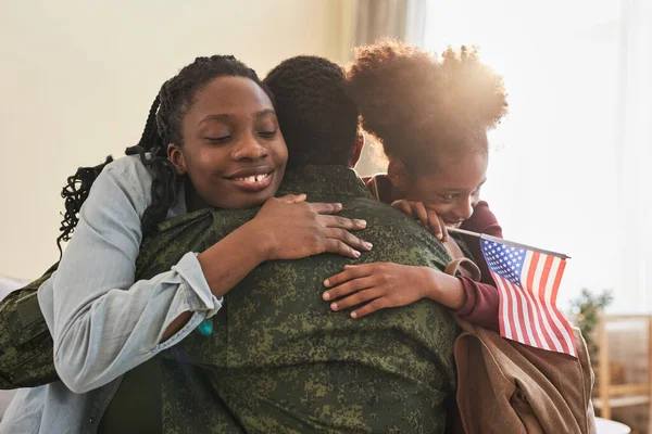 Family meeting their military dad, mother and daughter embracing him at home