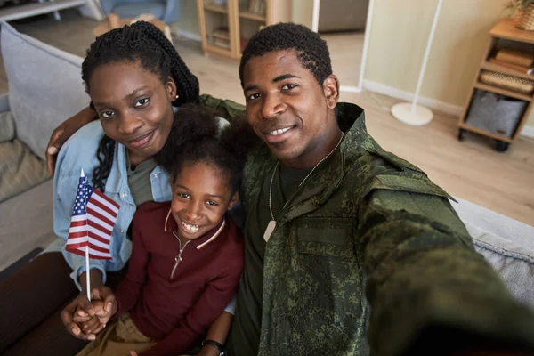African American military dad making selfie portrait with his family while they sitting on sofa in the living room
