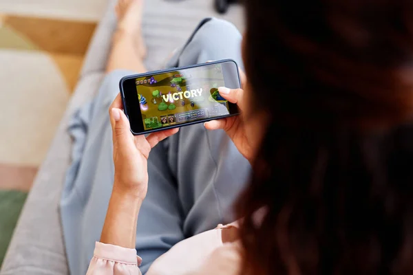 Close up of woman playing mobile game via smartphone with focus on victory word on screen
