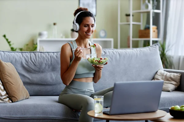 Portrait of sportive young woman eating fresh salad while enjoying healthy lifestyle and organic eating at home
