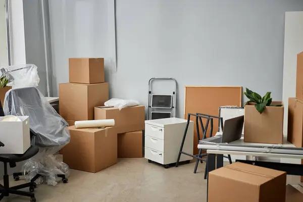 Horizontal image of packed things in cardboard containers and furniture preparing for moving in office