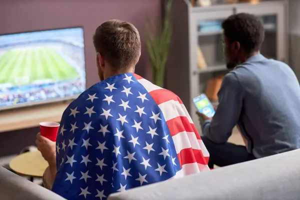 两名男子穿着美国国旗在电视上观看足球比赛的背景图 — 图库照片