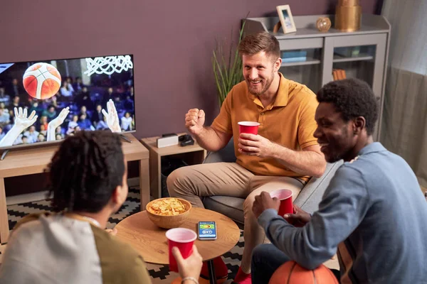 High angle view at group of sports fans watching match at home on TV and cheering