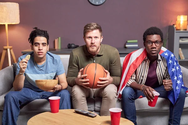 Diverse group of friends watching sports match at home with intense face expression