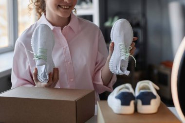 Genç ve mutlu tüketicinin abonelerine yeni spor ayakkabıları gösterirken paketsiz spor giyim videoları çekerken yakın plan görüntüleri.