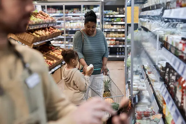 スーパーマーケットの設定は 少女との食料品のためのショッピング黒人女性に焦点を当てています — ストック写真