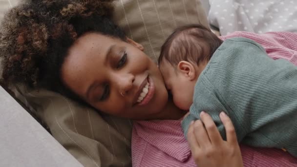 彼女の胸に小さな赤ちゃんとソファーに横たわっている若い幸せな黒人女性のトップビューショット — ストック動画