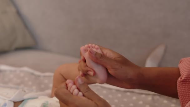 優しさと小さな赤ちゃんの足をマッサージする母親の世話の手 — ストック動画