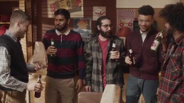民族的に多様な男性ギークのチームのドリーアウトショット ビールのボトルを凝視し ハイテクスタートアップの成功を祝う古風なアパートで一緒に取得しながらチャット — ストック動画