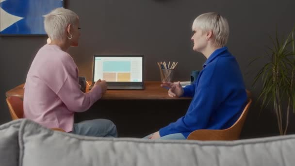 两名年轻的白种人聋哑女人在家里工作时 一边看笔记本电脑 一边用手语进行讨论 回放中镜头 — 图库视频影像