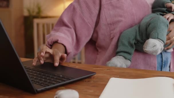 育児休暇中に自宅からフリーランスで作業しながら ラップトップコンピュータでアームブラウジングをしている若い肯定的なBiracialの母親を待って — ストック動画