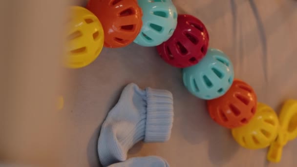 没有人在木制婴儿床的床垫上拍到浅蓝色的小婴儿袜和五彩缤纷的玩具 — 图库视频影像