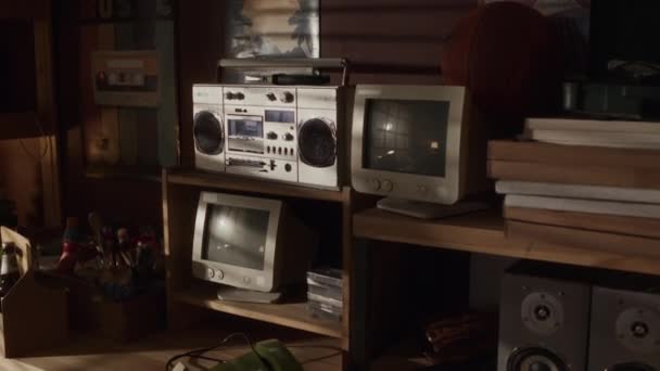 80年代风格 光线昏暗的车库里 没有人在木制货架上拍摄老式收音机盒式磁带录音机 老式计算机显示器 扬声器和瓶装啤酒 — 图库视频影像