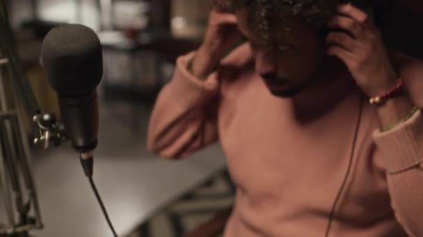 Tilt Shot Biracial Guy Light Pink Knitted Sweater Putting Headphones — Vídeos de Stock