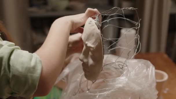 Plan recadré de sculpteur méconnaissable pliant les fils d'armature tout en façonnant la forme du crâne humain, faisant buste de femme en atelier