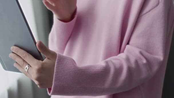 デジタルタブレットでビデオチャット中にサイン言語で話すパステルピンクのスウェットシャツで認識できない女の子のクロップショット — ストック動画