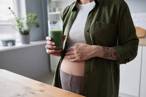 早间饮用绿色冰沙的怀孕年轻女子的卧床 以腹部为重点 复制空间 — 图库照片