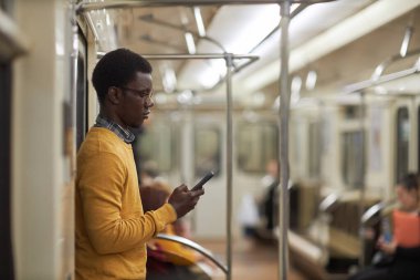 Afrikalı Amerikalı adam metro vagonunda kitap okuyor.