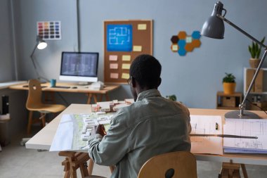 Modern ofisindeki iş yerinde inşa projesi geliştiren Afrikalı Amerikalı mühendisin arka görüşü