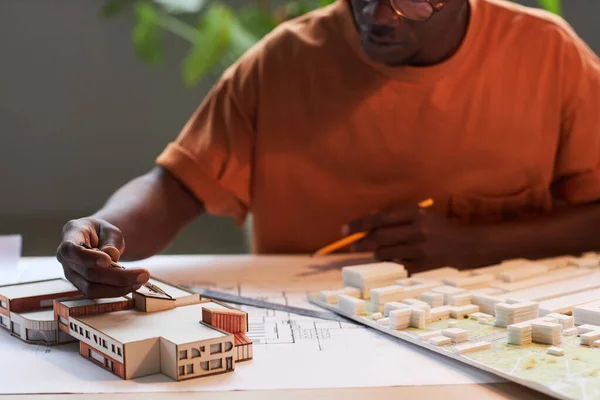 Close-up of African American architect drawing blueprint of new buildings at his workplace in office