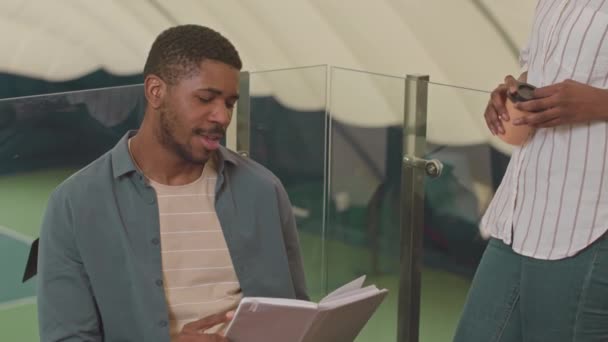 2人のアフリカ系アメリカ人男性と女性テニスコーチが屋内コートでゲーム戦略を議論 — ストック動画
