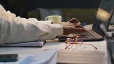 Tanımlanamayan siyah erkek ofis çalışanının son teslim tarihine yetişmek için gece ofisinde çalışırken dizüstü bilgisayarda yazı yazması.