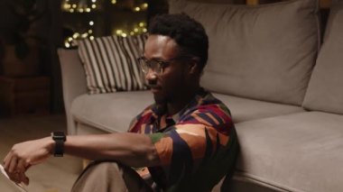 Kameraya poz veren genç yakışıklı zencinin yavaş yavaş portresi modern oturma odasındaki kanepeye yaslanmış, gece vakti evrak işleriyle uğraşırken.