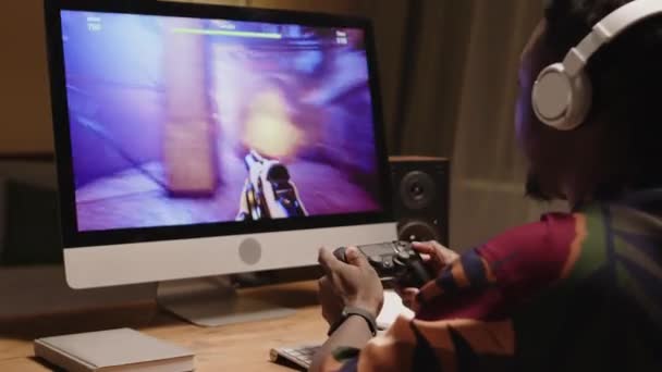 집에서 컴퓨터에서 Fps 비디오 게임을하는 컨트롤러를 사용하여 화려한 셔츠와 헤드폰에 — 비디오