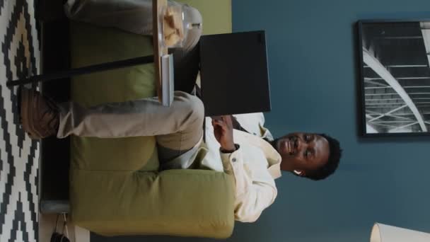 一个积极的年轻自由职业黑人男子坐在芥末软沙发上 与同事或朋友在笔记本电脑上视频聊天 — 图库视频影像
