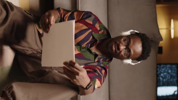 Kablosuz Kulaklıklı Genç Afrikalı Amerikalı Adamın Elinde Kağıtlarla Koltuğa Oturup — Stok video