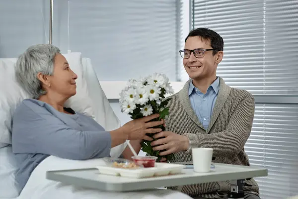 Poika Vierailee Vanhemman Äitinsä Sairaalassa Kuntoutuksen Aikana Antaa Hänelle Kukkia — kuvapankkivalokuva