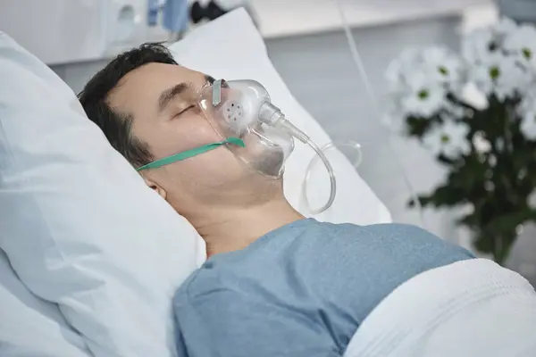 Young patient with oxygen mask lying in hospital ward during his rehabilitation