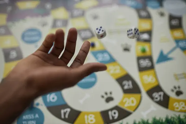 Close up of black male hand throwing dice making a move in board game, copy space