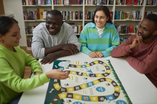 Diverse group of friends playing board game together at table and having fun, copy space