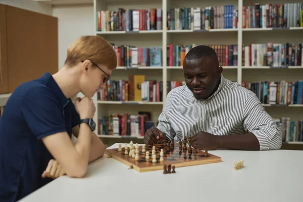 两个人在图书馆下棋的画像 重点是黑人男子思考获胜的策略 抄袭空间 — 图库照片