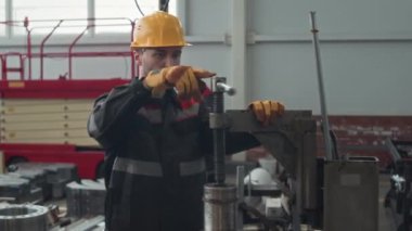 Kafkasyalı işçi erkek, kafkaslı, eldiven takmış ve tezgahta metal makine ekipmanları monte ederken orta boy bir fotoğraf.