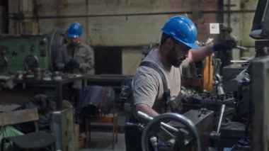 Metal fabrikasında gece vardiyası sırasında torna makinesinde özel donanım araçları kullanarak Orta Doğulu erkek endüstriyel mühendisin orta boy görüntüsü.