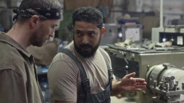 Orta Doğulu işçiler yeni metal fabrikası çalışanlarına torna makinesini çalıştırmayı öğretiyor.