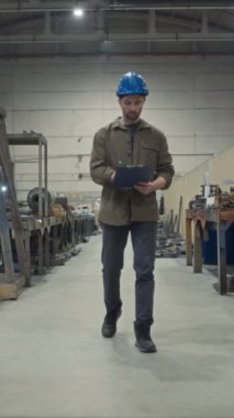 Kafkas ustabaşının gündüz vardiyası sırasında metal fabrikasında teftiş yaparken mavi şapkalı dikey olarak panoya bakması tam boy yavaşlıktır.