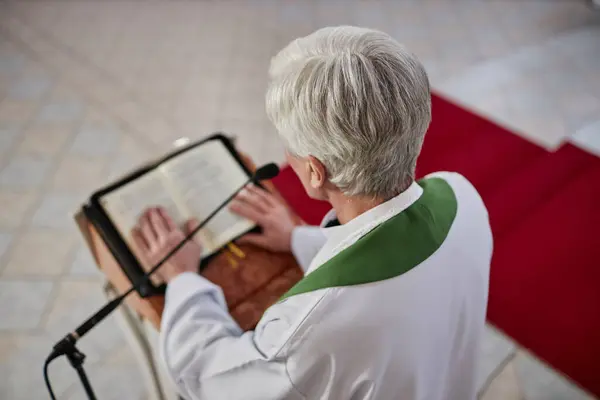 大祭司站在教堂圣坛后面用麦克风朗诵圣经的高透视 — 图库照片