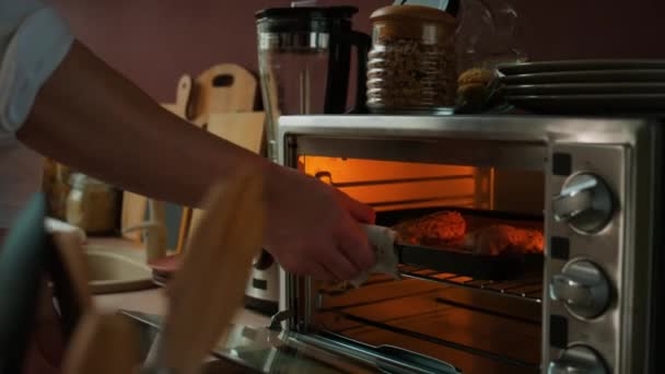 从电动小烤箱中取出两片烤鸡胸肉片 拍下的无法辨认的男性厨师的照片 — 图库视频影像