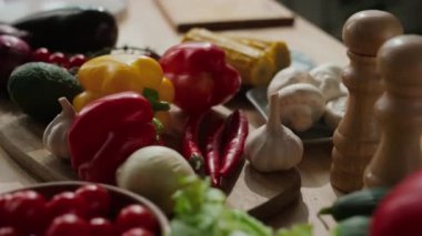 Çilekli domates, dolmalık biber, sarımsak vs. gibi taze sebzeler ahşap mutfak masasında.